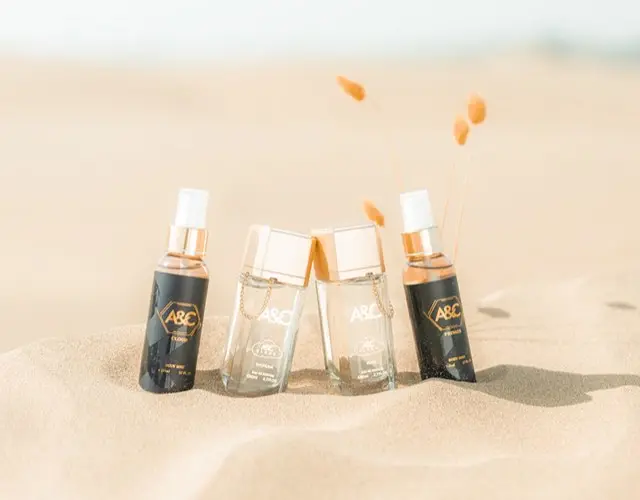 أربع عبوات عطر من A&C مغروسة في الرمل مع عشب جاف
