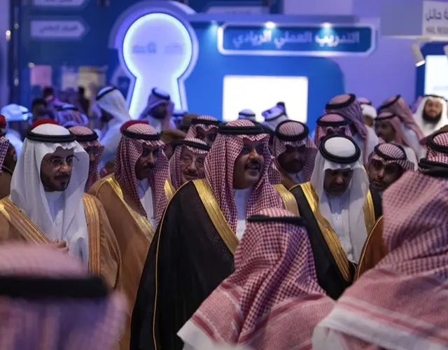 ضيوف بالبشوت والشماغ يمشون في قاعة فعالية كفيلة